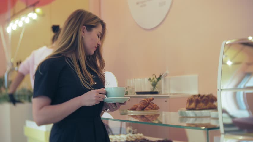 She buyer chooses yummy. Young attractive girl, woman buys in the coffee shop or pastries, cakes, cake, macaroon. A buyer standing under a a glass case at the bakery, coffee shop 4k