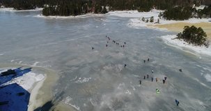 Aerial footage of frozen sea, big group of people are skating on the ice.