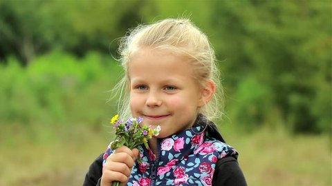 
A portrait of a cute little girl. Beautiful Little girl enjoys the smell of flowers in the meadow. having fun outdoor