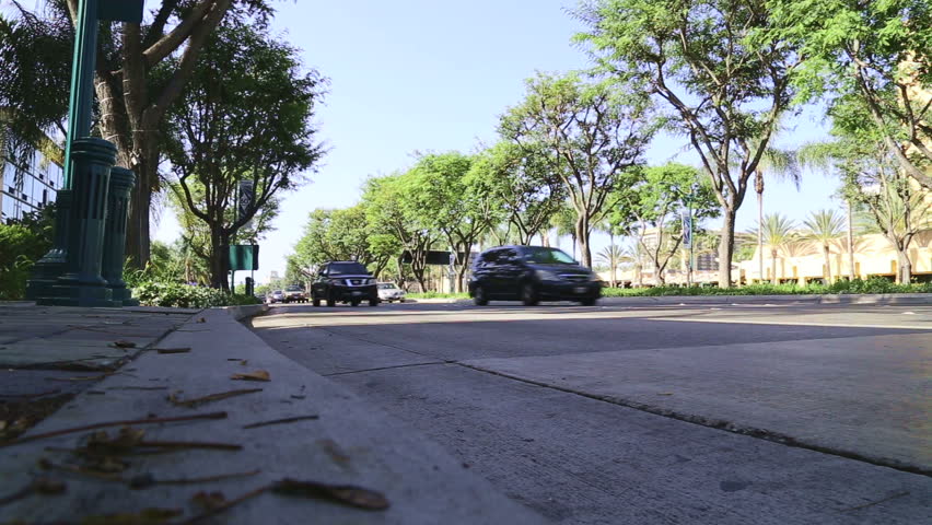 Wide angle low shot of traffic passing from a road in Anaheim while waiting for a bus.
