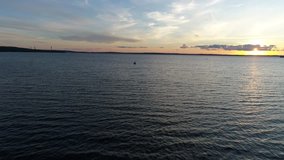 Fishing motorboat moving forward on lake at sunset. Camera moving toward the boat.