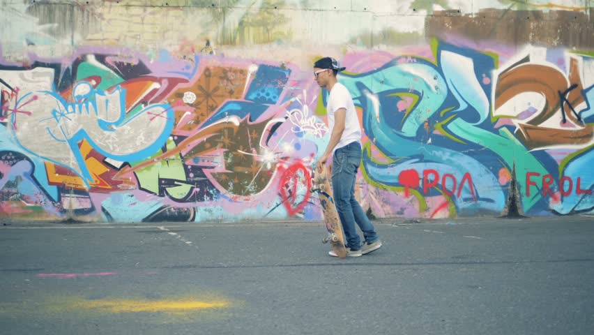 Skater jumps on a colored wall background, slow motion.