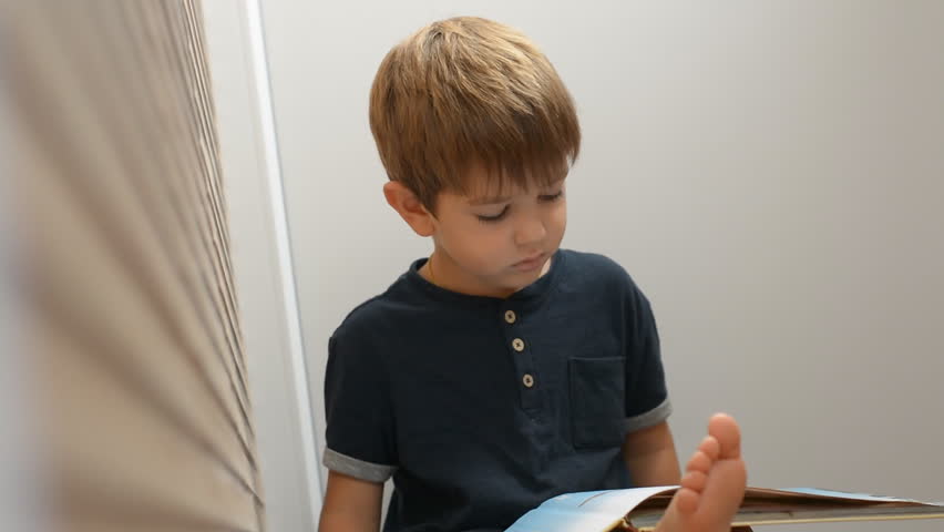 Learning process. A little boy thumbs through the pages of a large book. Close-up.