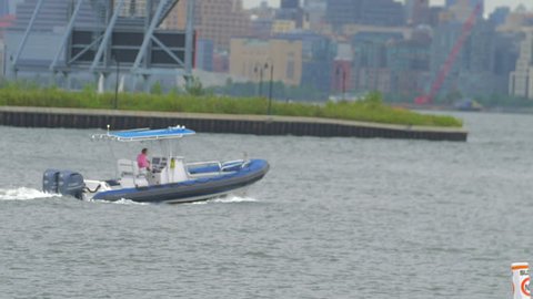 Covered motor boat sailing in bay in front of Manhatten