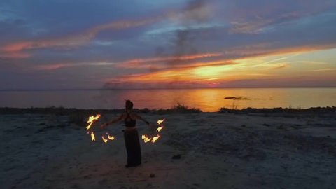 Beautiful woman walks to the river holding burning fire fans
