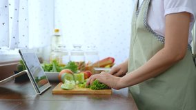 4K. female hand slicing fresh lettuce, prepare ingredients for cooking follow cooking online video clip on website via tablet. cooking content on internet technology for modern lifestyle concept