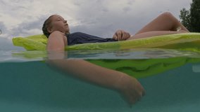 Underwater view of girl floating on pool raft in swimming pool / Cedar Hills, Utah, United States