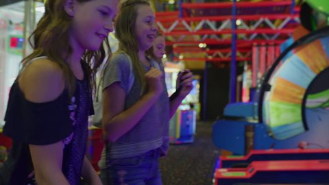 Panning shot of happy girls playing skee ball in arcade / Orem, Utah, United States