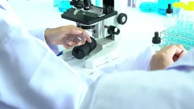 Scientist female is looking through microscope with colleagues working in modern laboratory or medical center together. Concept of science, testing development and lab industry.