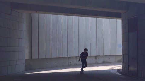 KIEV, Ukraine - August 17, 2018: Young skateboarder guy leaves the tunnel on the board