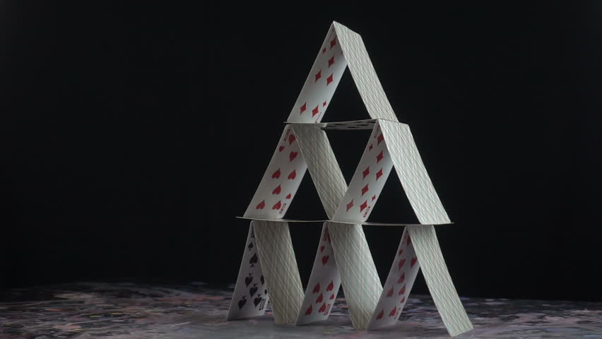 This stock video shows a stack of playing cards built into a castle. The cards topple down on its own weight. This clip is perfect for projects about the fall of a business or empire.  Royalty-Free Stock Footage #1017003862