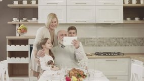 Happy Family Uses A Tablet For Video Communication. Family Toasting At Dinner Table At Home In Kitchen