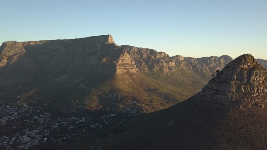Panning drone shot of iconic angle of lions head and table mountain at sunset in Cape Town, South Africa.