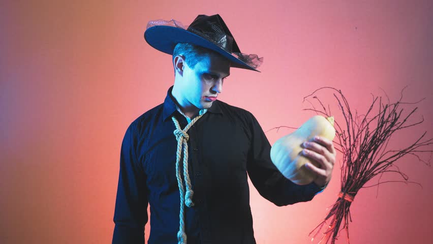 young man in a zombie costume for halloween, with pumpkins in his hands. 4k, slow motion. close-up