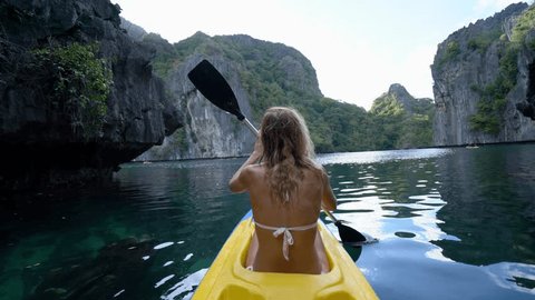 Woman exploring calm tropical bay with limestone mountains by kayak in the Philippines. People travel destinations tropical beaches concept ; People discovery adventure in holidays