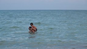 A boy jumps into the water from his father's shoulders Slow motion video