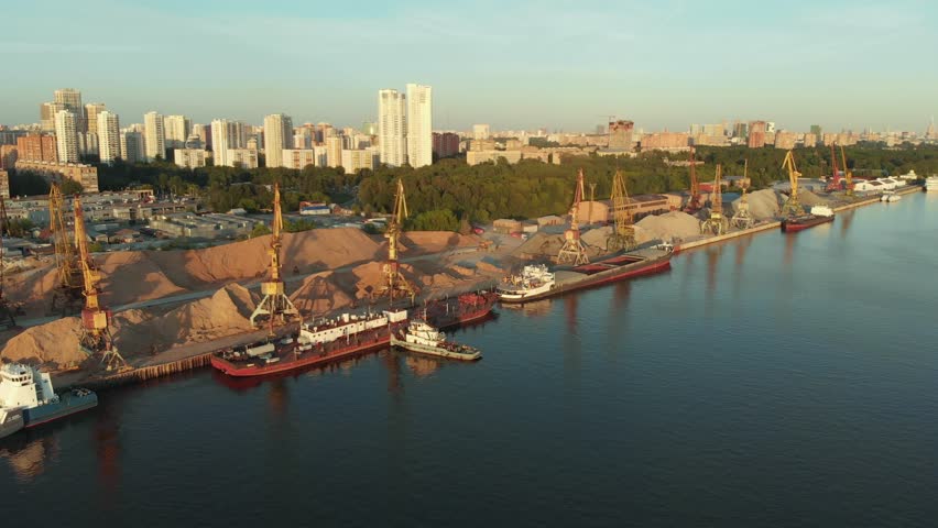 Panoramic view on river port with fleet barges anchored in water next to the river bank. Landscape with great wavy river