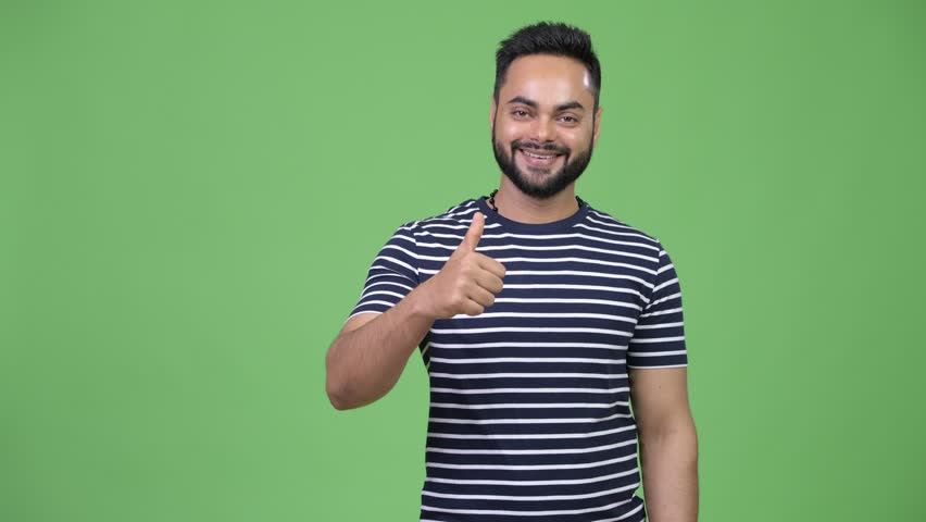 Young happy bearded Indian man giving thumbs up