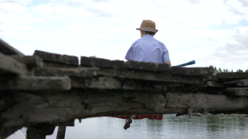 boy is fishing on the old pier in the river