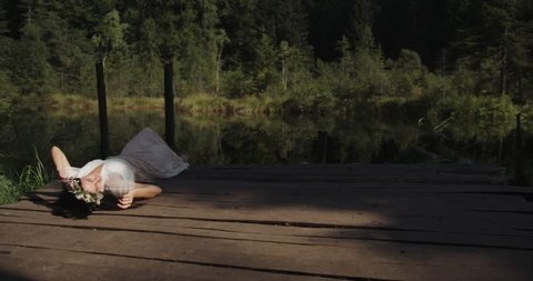 Forest nymph. Beautiful woman in white dress rests on a bridge over mountain river in the rays of morning sun