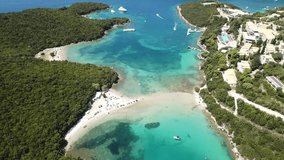 Aerial drone bird's eye view video of popular and iconic turquoise beach of Bella Vraka in island of Mourtemeno with sunbeds and canoes forming a blue lagoon, Sivota bay, Ionian, Epirus, Greece