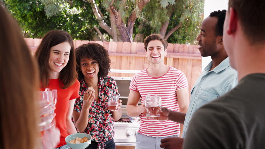 Young adult friends standing with drinks at a backyard party | Shutterstock HD Video #1017037537