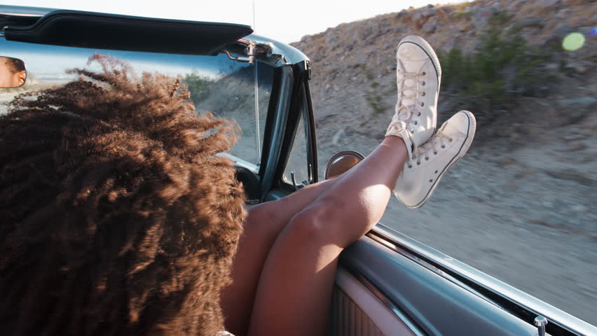 Young couple driving open top car, woman\xD5s legs over door