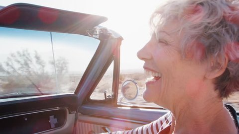 Happy senior female passenger in a convertible car, close up