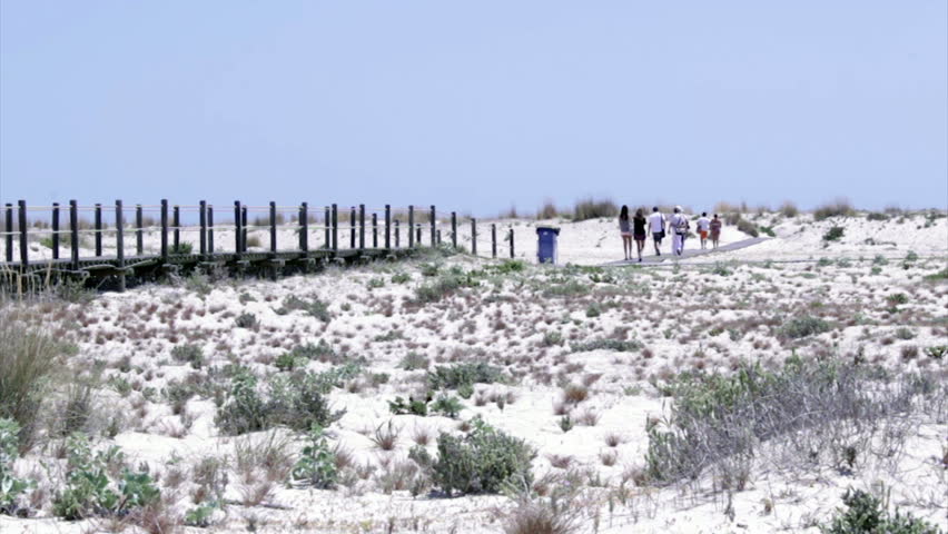 Tourists in footpath acess to Armona cost beach, one of the islands of Ria Formosa wetlands natural park, Algarve, southern Portugal.