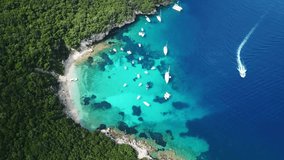 Aerial video of tropical exotic paradise vegetated island with blue lagoon, white sandy beaches and turquoise sea with sail boats and yachts docked