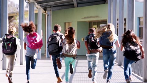 Elementary school kids run from camera in school corridor
