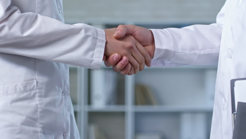 Close up shot of two unrecognizable people in lab coats standing in office and shaking hands after reaching agreement | Shutterstock HD Video #1017045271