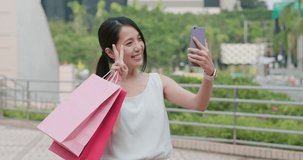 Woman hold shopping bag and taking selfie on mobile phone
