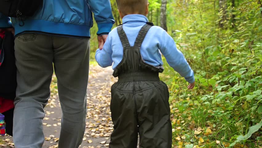 A young father walks in the autumn Park with his child. The father holds his son