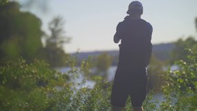 Man taking video and photo in forest on summer day wearing backpack and baseball cap 03