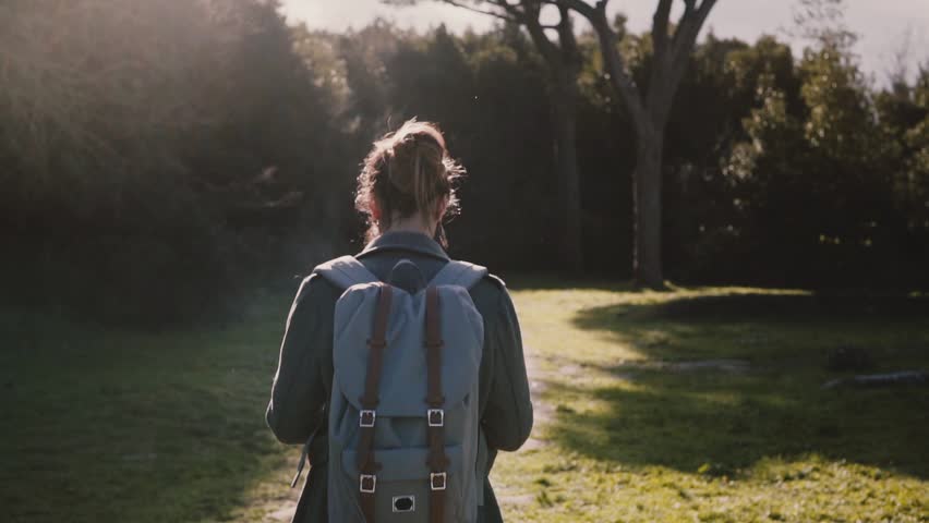 Camera follows beautiful girl with backpack and map exploring ancient summer sunny forest road in Ostia slow motion.