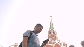 Travel and technology. Happy tourist man looks the navigator smartphone taking selfie with backpack. slow motion lifestyle video. on Red Square in Moscow, Russia. tourist journey travel man in Russia