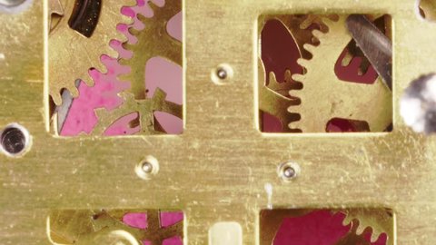 close up and zooming out detail of running clock or watch machinnery on a pink background. Copy space available and suitable for time concepts