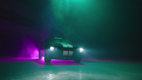 Silhouette of beautiful american muscle car on smoked dark background . Car lights on fog . 