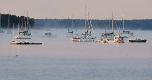 Telephoto view of the boats at anchor at Stockton Harbor in Stockton Springs Maine with birds flying and floating on the water.