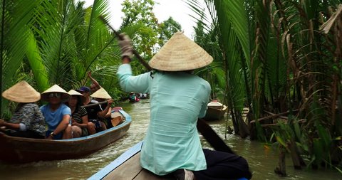 Mekong Delta, Vietnam - June 15, 2018: Vietnamese woman rowing sampan boat along natural canals near My Tho in the Mekong Delta, a vast maze of rivers, swamps and islands in southern Vietnam.