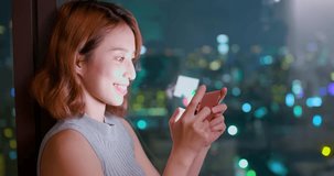 woman play mobile game happily in building at night