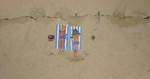 Aerial Rising: Couple Sunbathing on the Beach