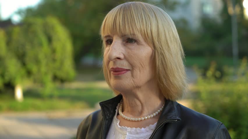 portrait of mature smiling woman in the park,4k 3