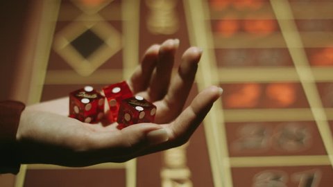 Player hand throwing red dices on gambling table. Entertainment and leisure in vegas casino. Close up woman hand holding three dices. Gambling game in craps at casino. Gambling addiction concept