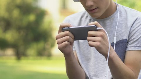 Teenager playing video game on phone, nervous and irritated, gaming disorder