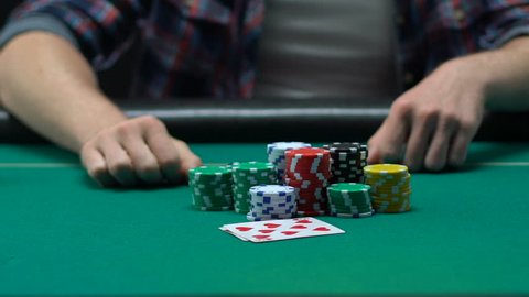 Risky man betting all chips in while playing poker in casino, gaming addiction