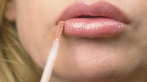 super close-up, slow-motion, 4k. a woman is painting lips with lip gloss. lip makeup, dermatological disease on the skin of the lips. Fox Foxes granules