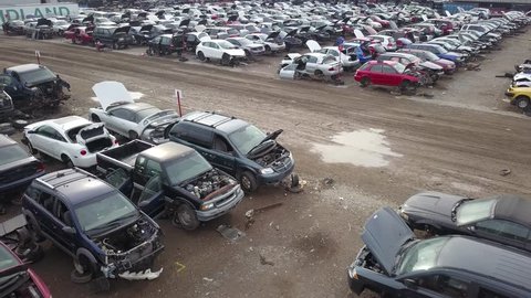 Aerial drone footage of a junk yard with row after row of wrecked cars.