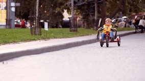 Happy child on red bike having fun outdoors. Active kid boy riding retro stylish bicycle. Cute smiling little boy playing and cycling on street road and spending family time. Slow motion video.